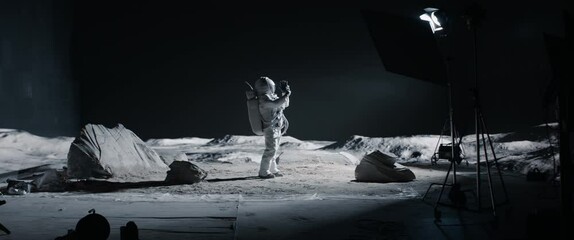 Wall Mural - wide male actor in astronaut suit making selfie on a moon lunar movie shooting set. shot with 2x ana