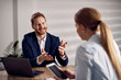 © Drazen - Happy businessman talking with female colleague while working in the office.