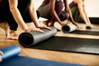 © Drazen - Close-up of athletic woman rolling up her exercise mat after practicing at health club.