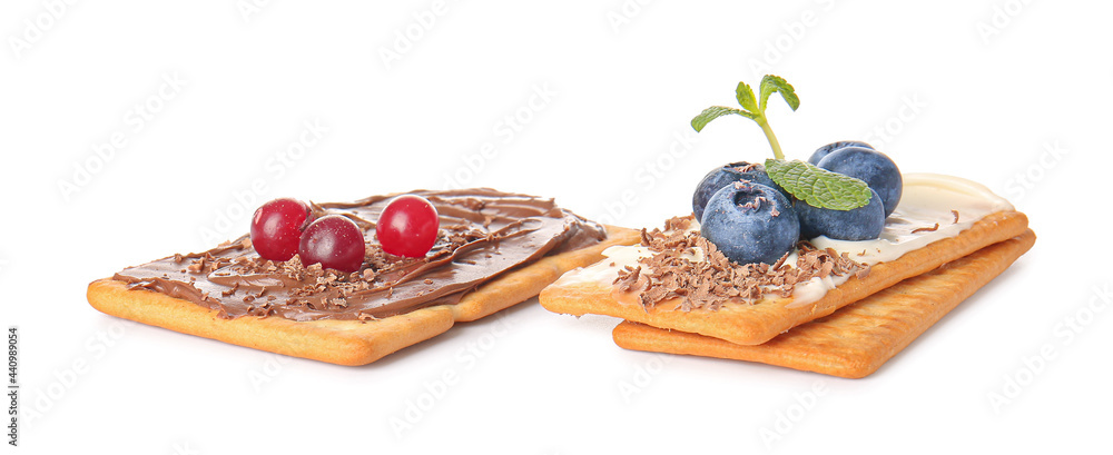 Tasty crackers with berries and chocolate on white background