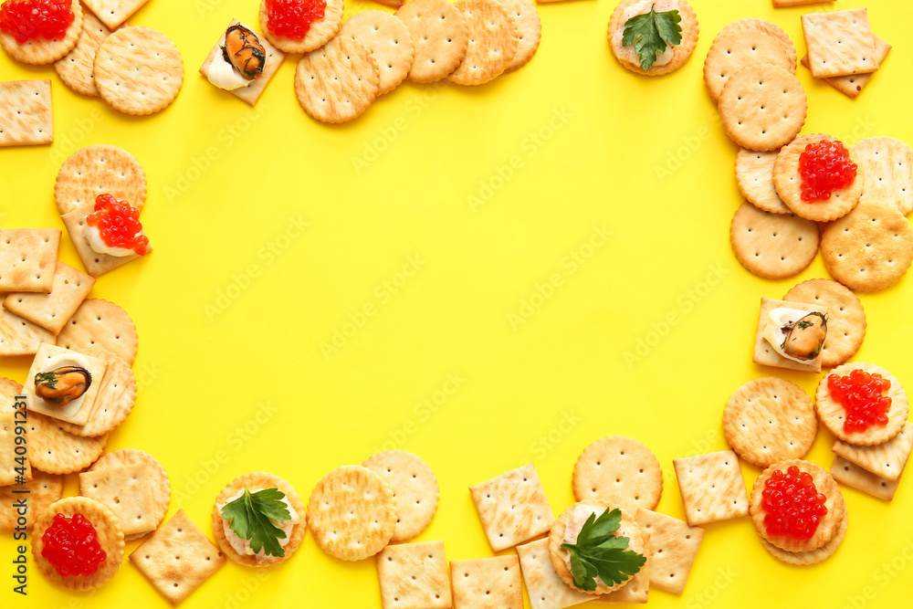 Frame made of tasty crackers on color background
