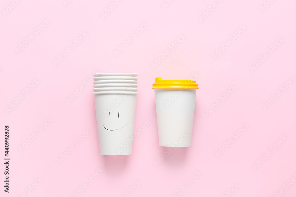 Takeaway cups for coffee with drawn smile on color background