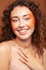 young pretty girl with blond curly hair posing cheerful on brown background, lifestyle people concept