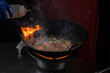 Funchoza flambe rice noodles with vegetables cooking on fire in wok pan. Street food.