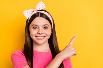 Wall Mural - Photo of sweet adorable school girl wear pink t-shirt pointing finger empty space smiling isolated yellow color background