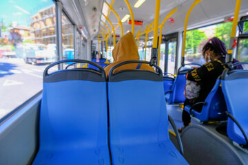 Defocused people on the bus. Empty blue seats in a bus close-up. Public urban transportation	
