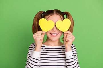 Poster - Photo of pretty blond hairdo little girl hold hearts wear striped sweater isolated on green color background