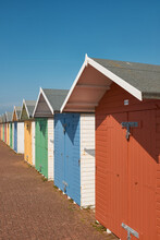 Brightly Coloured Beach Huts With Diminishing Perspective  Against A Clear Blue Sky.