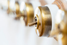 Retro Style Brass Power Switches On White Wall. Brass Vintage Switch On Interior Wall.