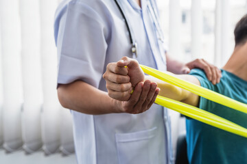 Close-up of a physiotherapist hand helping a patient stretch his arm using a cloth at the clinic.