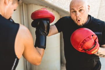 Sticker - Two men exercising and fighting in outside. Boxer in gloves is training with a coach