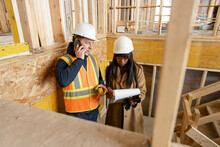 Homebuilders With Clipboard Meeting At Home Construction Site