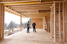 Homebuilder And Homeowner Inspecting House Construction Site