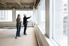 Project Manager And Client Looking Out Of Window Of Empty Office
