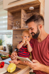 Canvas Print - Father and baby boy cooking dinner in kitchen