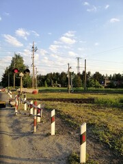 a flashing red railway traffic light or a checkpoint at a railway crossing on  background of a road, field and village houses