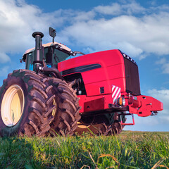 powerful agricultural tractor among the field against the blue sky