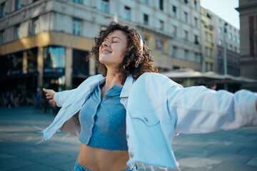 portrait of a girl with curly hair dressed casually standing outdoors and smiling.