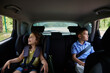 © Taras Grebinets - Buckled children, boy and girl, traveling in a safety booster seat inside the car. Safe travel with children in the car