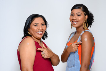 smiling mother and daughter showing the vaccine sticker on their arm