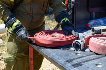 Sticker - Person in fireman uniform packing a red water hose into a spiral