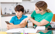 © JackF - Portrait of boy using mobile phone during homework and his displeased mother