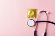 © sorapop - World sexual health or Aids day, Top view flat lay medical equipment, condom in pack and stethoscope, studio shot isolated on a pink background, Safe sex and reproductive health concept