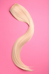 Strand of blonde hair on color background