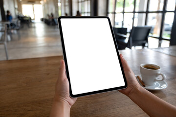 Mockup image of a woman holding digital tablet with blank white desktop screen in cafe