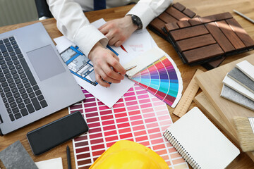 Wall Mural - Male designer architect picks colors from color palette at workplace