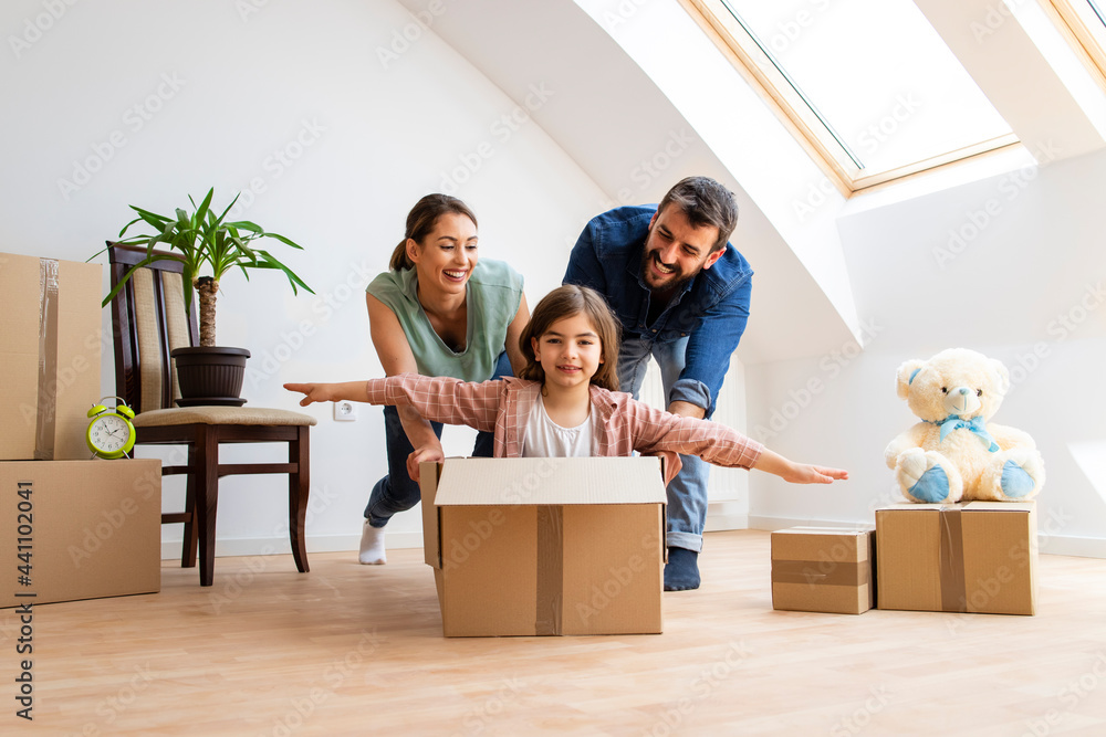 Home, people, moving and real estate concept - happy family with children enjoying very first day in new house and riding in cardboard boxes.