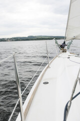 River boat trip. Details on a sailing yacht. We go by boat in the summer. White yacht with full sails running downwind wing-on-wing, sailing after the storm. Leisure activity, sport, recreation theme.