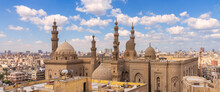 Aerial Day Shot Of Minarets And Domes Of Sultan Hasan Mosque And Al Rifai Mosque Mediating Shabby Buildings With Satellite Dishes In Cloudy Day, Old Cairo, Egypt