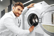 © fotofabrika - Young man choosing new washing machine in household appliances store