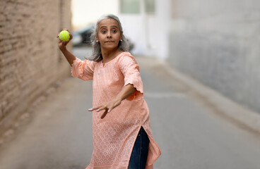 Wall Mural - An old woman playing cricket Bowling.