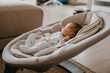© Bostan Natalia - Newborn baby sleeping in a swing, wearing a white onesie pajama.