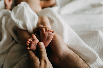father holding small newborn baby feet in his big hands.