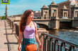 © KseniaJoyg - A beautiful young woman walks in the center of St. Petersburg on the embankment with a beautiful bridge