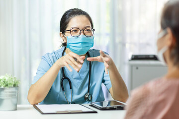 Wall Mural - Asian Female Doctor wearing protective face mask talking with Senior woman patient in medical room