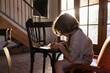 © Mint Images - young boy writing on small chair at sunset