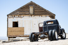 Abandoned Vintage Car In Front Of An Abandoned House In The Desert Against Sky