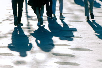 Shadows and silhouettes of people on a road during sunny evening.