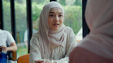 Young muslim woman talking with her friend in coffee shop