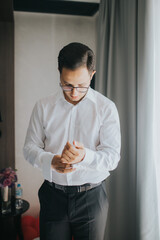 Wall Mural - Handsome groom getting dressed and preparing for the wedding