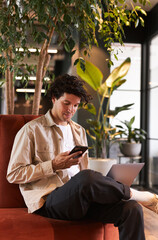 young man online with mobile phone in open plan office renting work space for start up business
