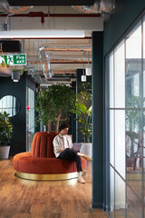 young man with laptop in seating area of open plan office renting work space for start up business