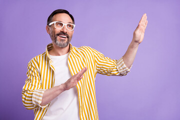 Poster - Photo of positive cheerful mature happy man look empty space raise hands dance isolated on violet color background