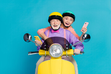 Poster - Photo of married old grey haired couple biker ride wear helmet hold phone isolated on blue color background