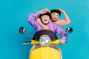 Poster - Portrait of two nice elderly retired pensioner friends riding bike looking far away having fun isolated over bright blue color background