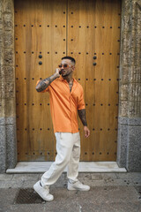 Wall Mural - Vertical shot of a male wearing casual clothes and using his phone by an old building in Spain